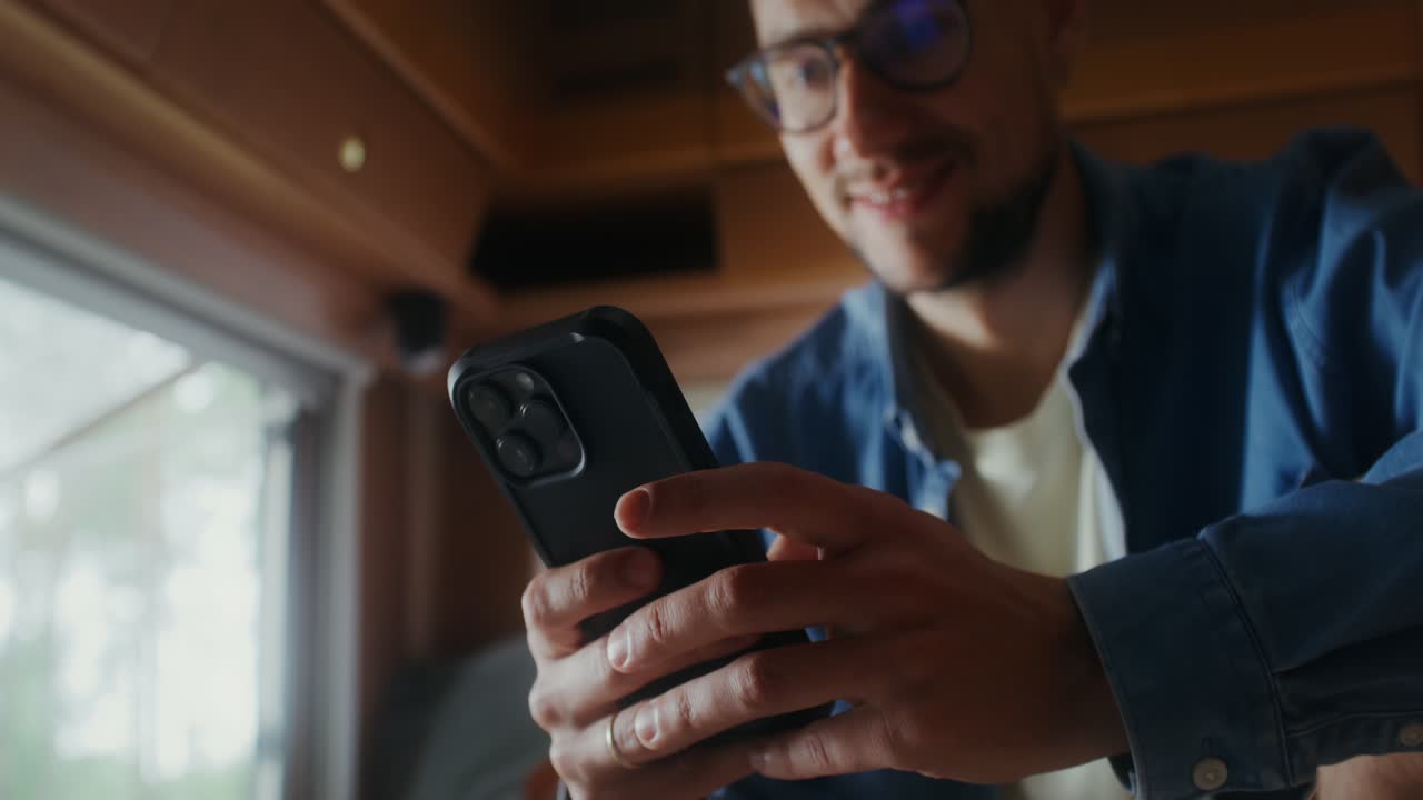 캠퍼 밴에서 스마트폰을 사용하는 남자