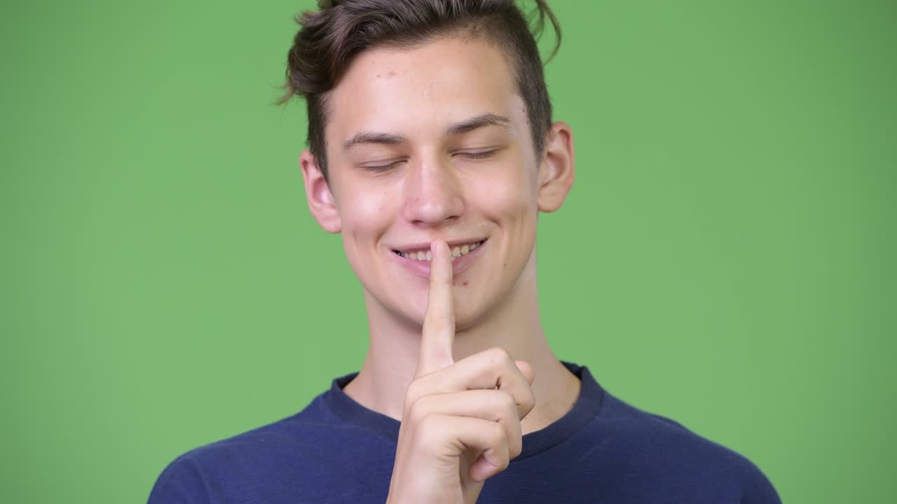 Young handsome teenage boy with finger on lips