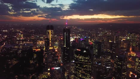 aerial view of a modern city with tall buildings, lights, central park and dramatic clouds at sunset