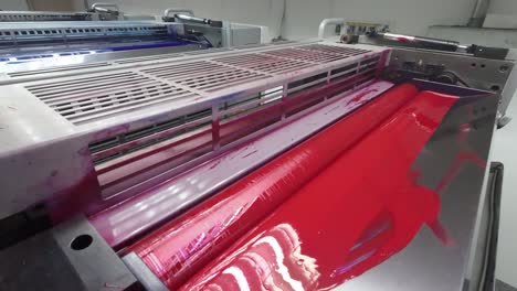 close up of a printing press roller covered in vibrant red ink