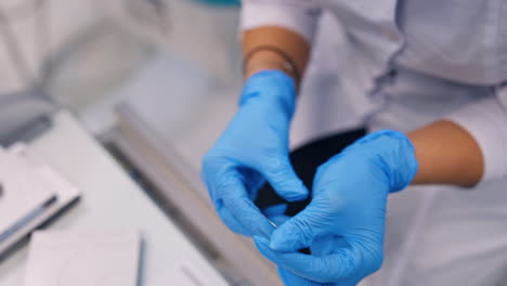 hands in latex gloves use metal tool to bend the wire. preparing the materials for orthodontic care. close up.