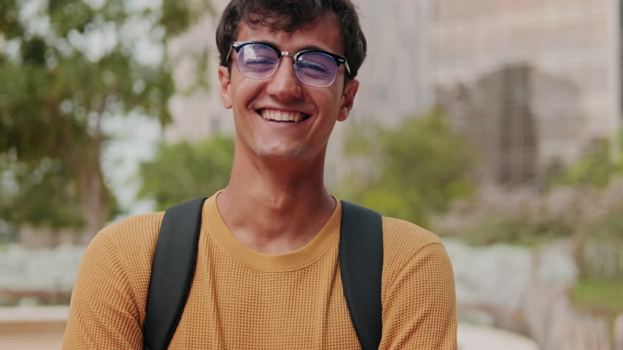 Portrait of European young man, cute geeky male studet smiling outdoors with