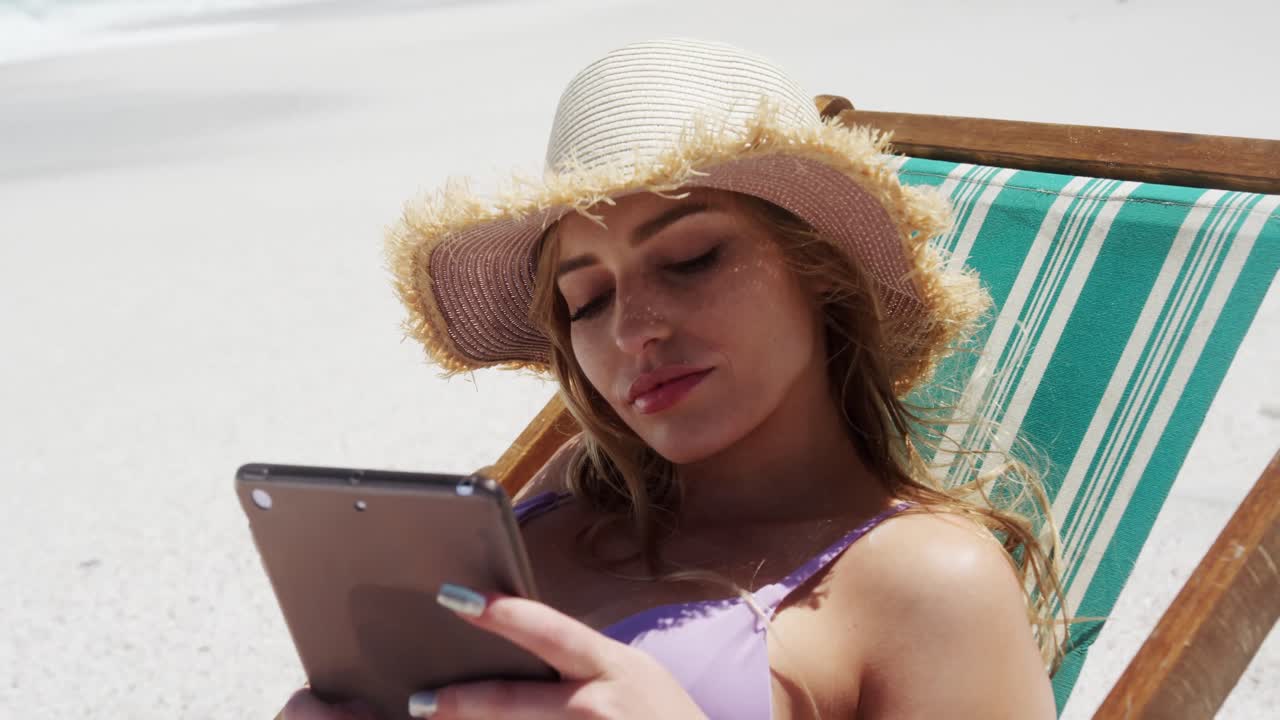 mujer usando una tableta digital en la playa