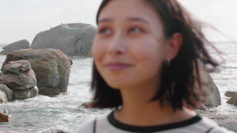 retrato de una hermosa mujer asiática sonriendo disfrutando de la playa nublada explorando el estilo de vida de vacaciones con el viento soplando el cabello en la playa