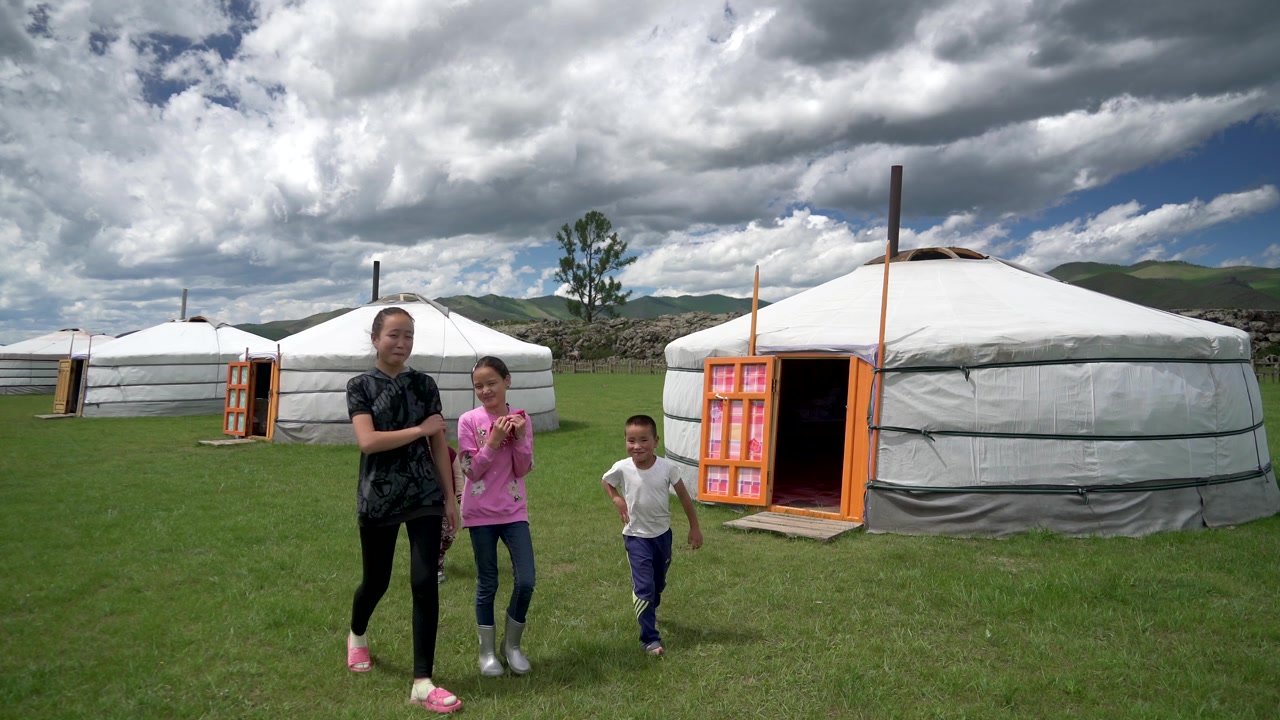 Skupina dětí procházející se poblíž tradičních mongolských jurt