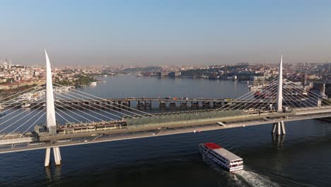 ferry boat passes under golden horn bridge as metro subway train departs station