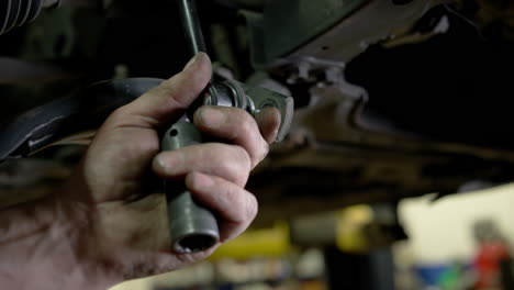 car mechanic at repair service station inspecting car suspension detail