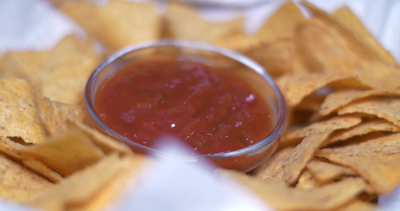Una ciotola di nachos e salsa di pomodoro che gira su un tavolo rotante