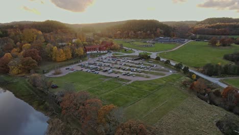 drone flying towards parking area of nordens ark hotel by aby fjord in bohuslan sweden on a sunset, aerial