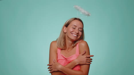 Smiling-positive-shy-angelic-woman-with-angel-halo-nimb-over-head-flirting,-looking-at-camera