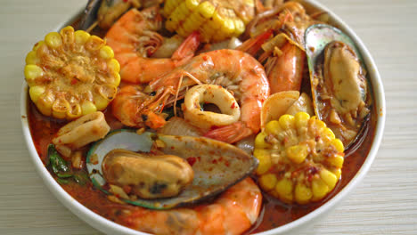 mariscos picantes a la barbacoa: gambas, calamares, mejillones y maíz.