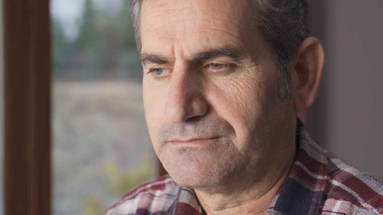 hombre infeliz mirando por la ventana.