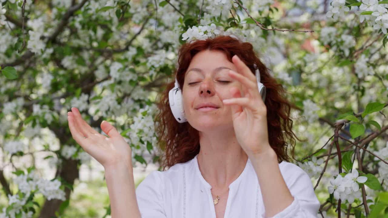 Woman listening to music in a blooming apple tree