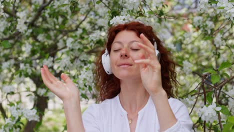 woman listening to music in a blooming apple tree