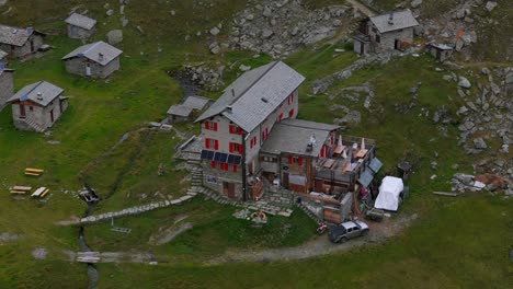 Aerial-Overhead-View-Of-Rifugio-Cristina-in-Valmalenco,-surrounded-by-wide-pastures-and-a-pretty-mountain-pasture,-Alpe-Prabello