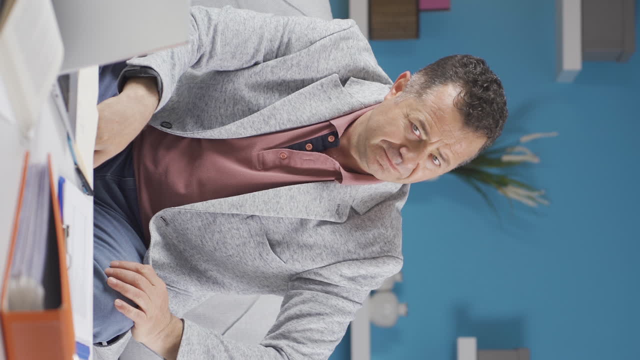 Vertical video of Home office worker old man looking at camera depressed.