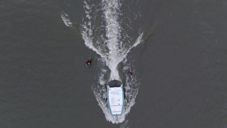 two hydro foiler surfing wave behind watercraft filmed with drone 90 degree