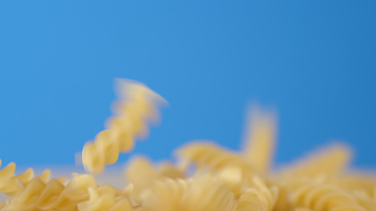 la pasta seca de fusilli cae sobre la mesa en una pila.