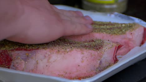 dos manos frotan especias y sal en un filete de costilla grueso y crudo preparándolo para ser asado
