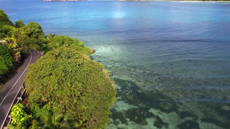 imágenes de drones que pasan sobre carreteras públicas de asfalto, árboles y océano índico, baie lazare, mahe, seychelles