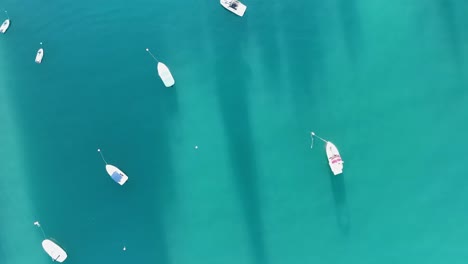 Toma-Aérea-A-Vista-De-Pájaro-De-Pequeñas-Embarcaciones-Ancladas-Y-Conduciendo-En-Aguas-Tropicales-Color-Azul-Turquesa-Cerca-De-La-Playa-Con-Lido-Y-Nadadores.