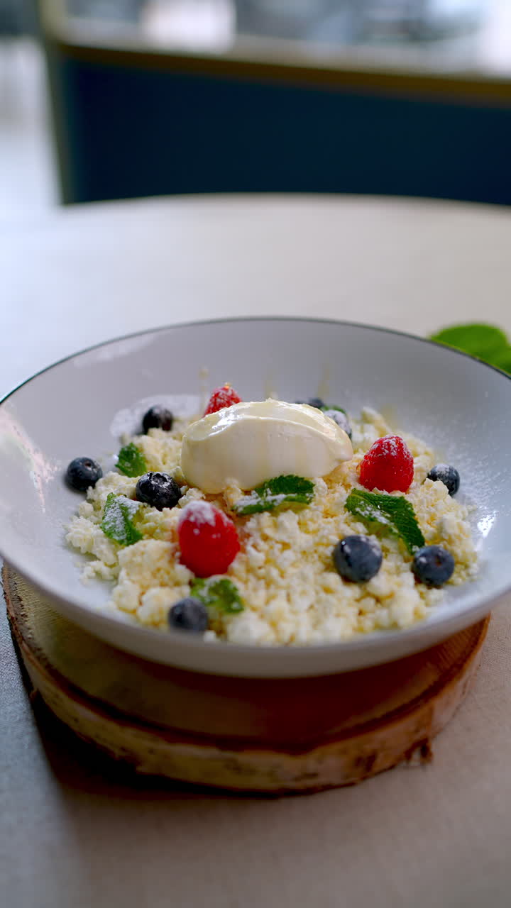 Eastern European cuisine presents a sweet cheese dessert, beautifully arranged on a plate with fresh berries and mint leaves, creating a visually appealing culinary experience