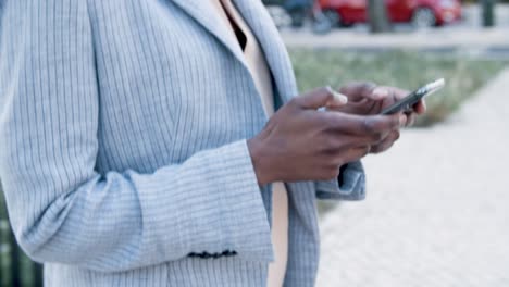 vista lateral de una mujer enviando mensajes de texto en un teléfono inteligente durante un paseo