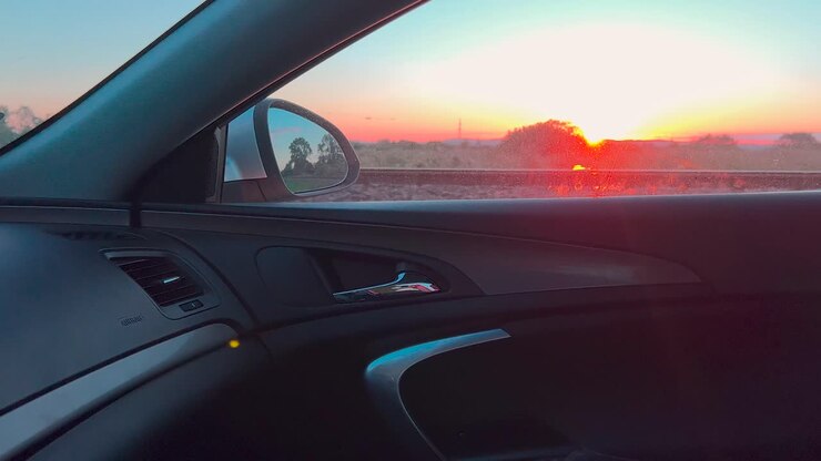 Auto che guida sulla strada con uno splendido paesaggio al tramonto attraverso il finestrino lato passeggero