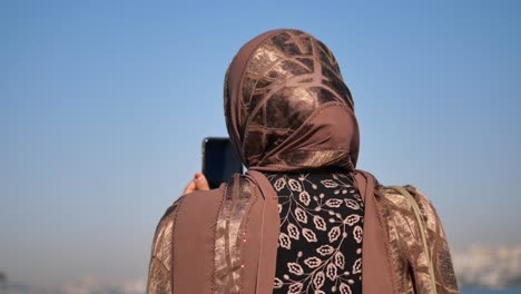 woman in hijab taking a photo with her phone