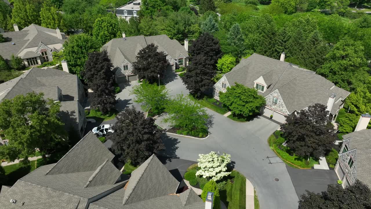 Drone view of townhomes on a cul-de-sac with mature trees in a private gated community