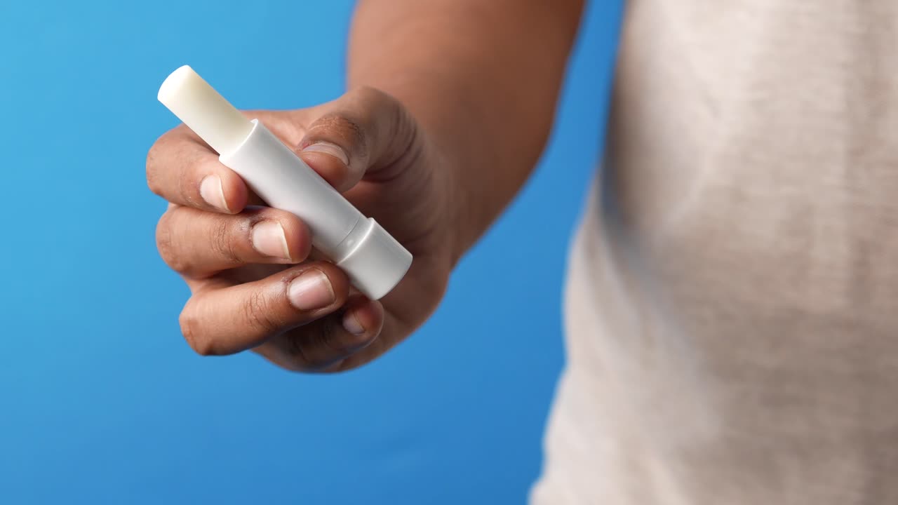 mano con un bálsamo para los labios blanco