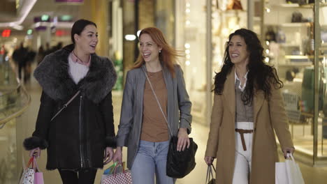 three women friends shopping and walking in a mall