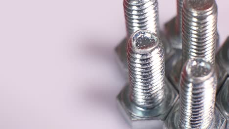 rotating group of galvanized metallic screws close-up. steinless steel bolts isolated on white background.