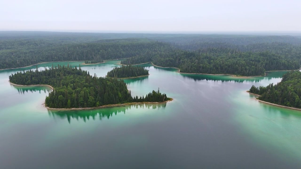 Vista aérea de ilhas florestadas cercadas por águas turquesa, verdes e azuis com margens arenosas no Lago Arnott, no norte de Ontário.