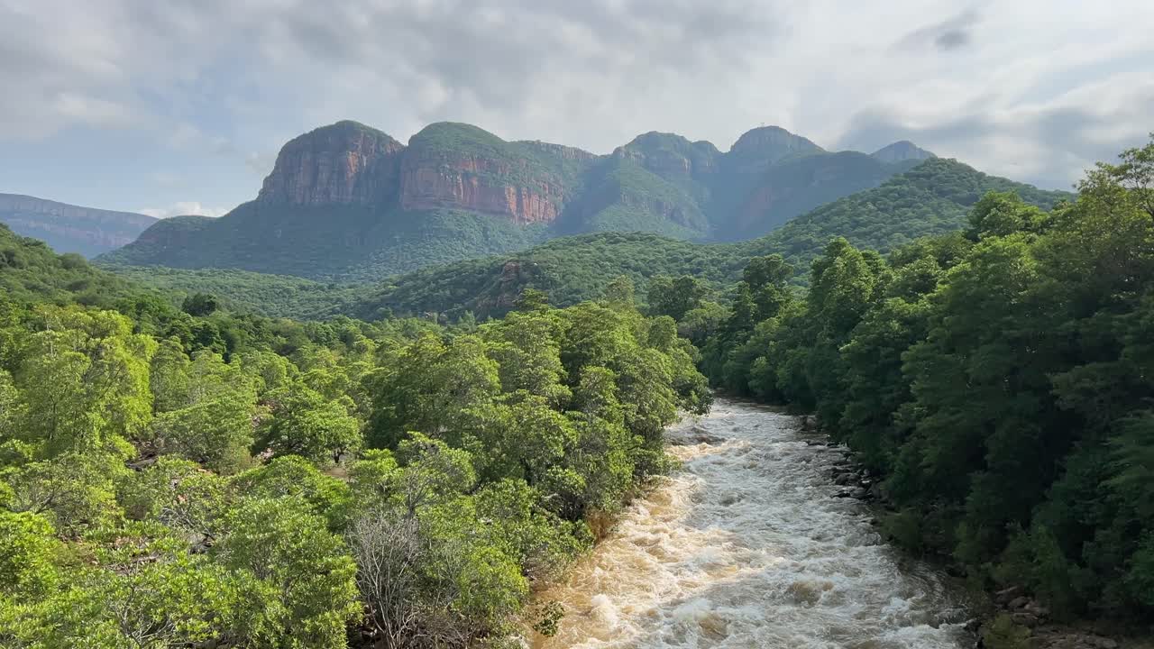 Fiume impetuoso torbido in piena con scogliere di faglia in lontananza, Africa