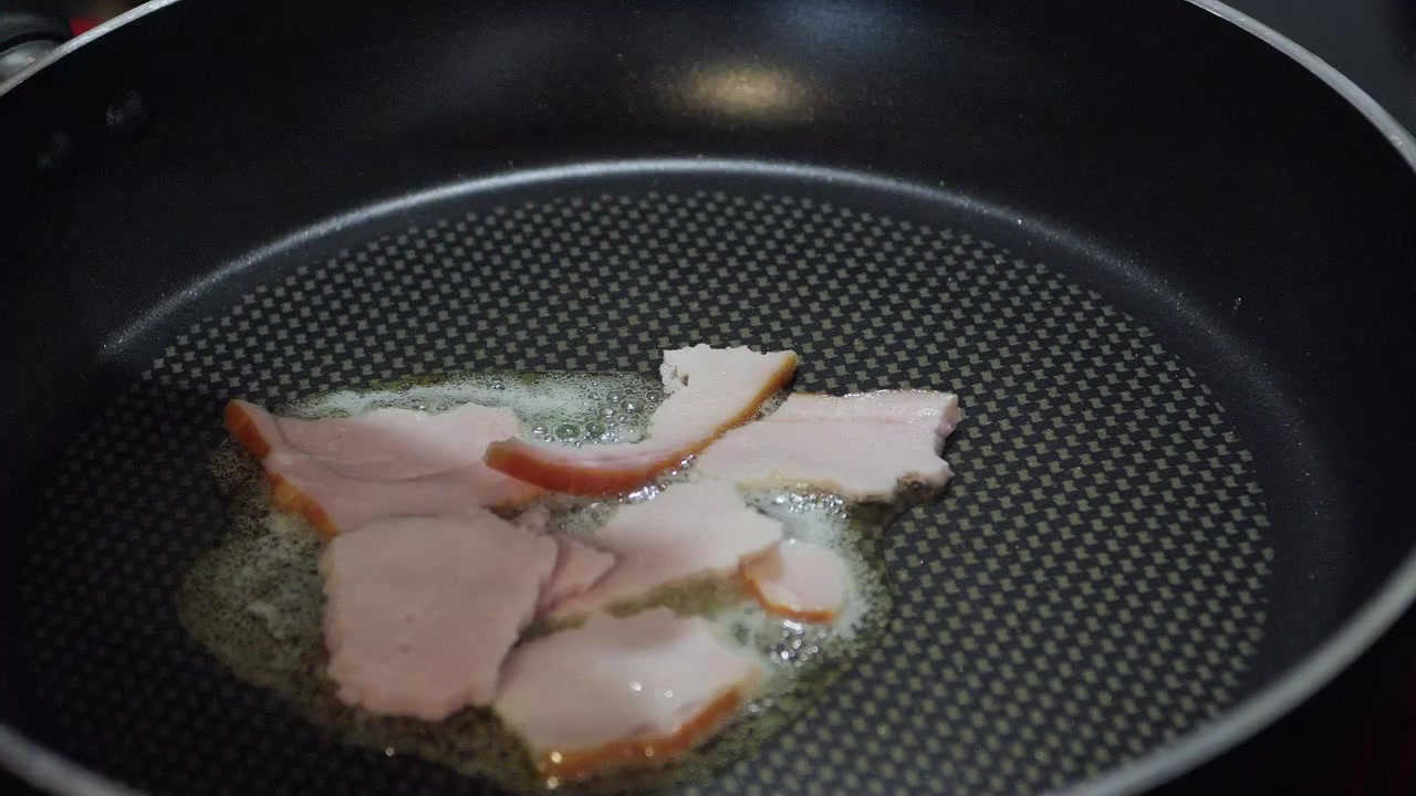 Primo piano di pancetta per la colazione che frigge con uova in padella