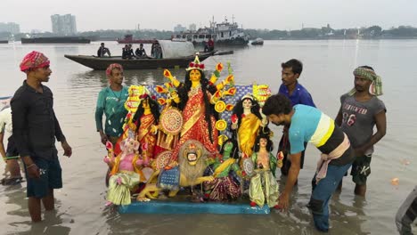 shot of durga idol immersed into holy ganga river during sunset on last day of navratri in kolkata, india. vijay dashami durga visarjan.