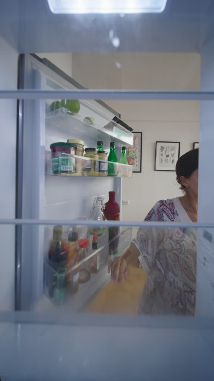 Woman checking food inside a refrigerator