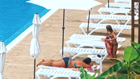 personas sentadas a la orilla de la piscina de un resort durante las vacaciones de verano