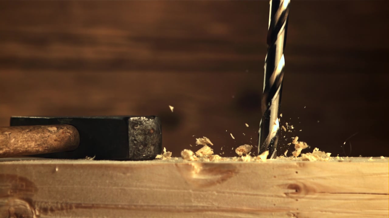 Primo piano di una punta da trapano che crea trucioli di legno mentre fora il legno
