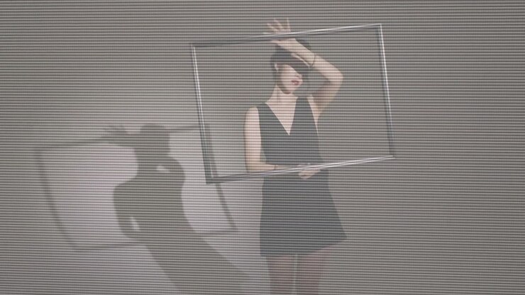 Woman holding metal frame and rotating it against plain wall, camera pushing in for portrait