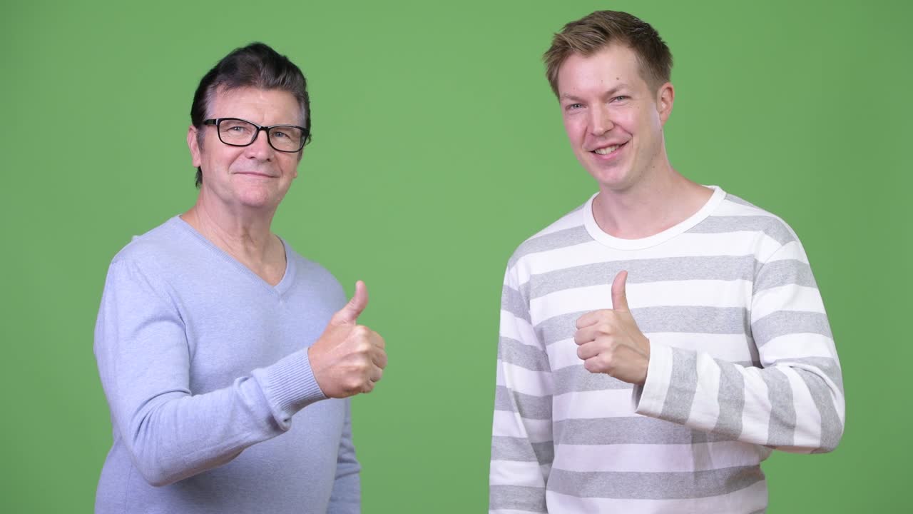 hombre guapo senior y hombre guapo joven dando pulgares hacia arriba juntos