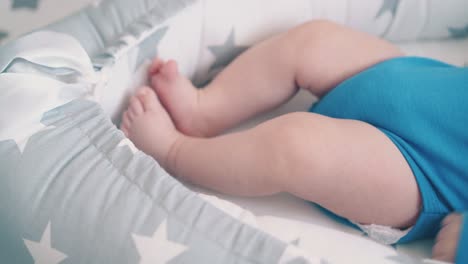 little baby kicks legs resting in soft cocoon in child room