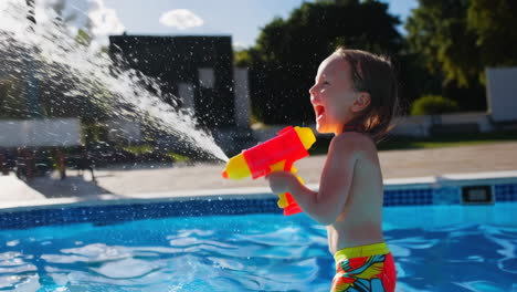 happy child playing with a water gun in a swimming pool