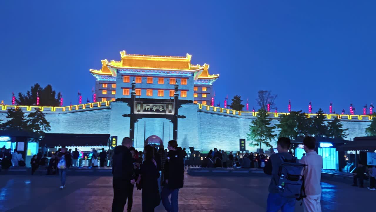 Tourists Enjoying Xi'an City Walls From Yongning Gate Illuminating Lights At Dusk In Xi'an, China. panning shot