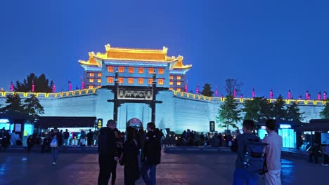 tourists enjoying xi'an city walls from yongning gate illuminating lights at dusk in xi'an, china. panning shot