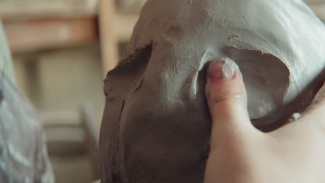 female sculptor forming facial features on clay head