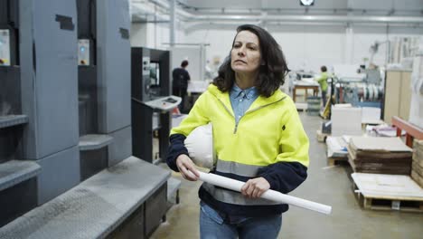 front view of serious female printing worker walking at plant