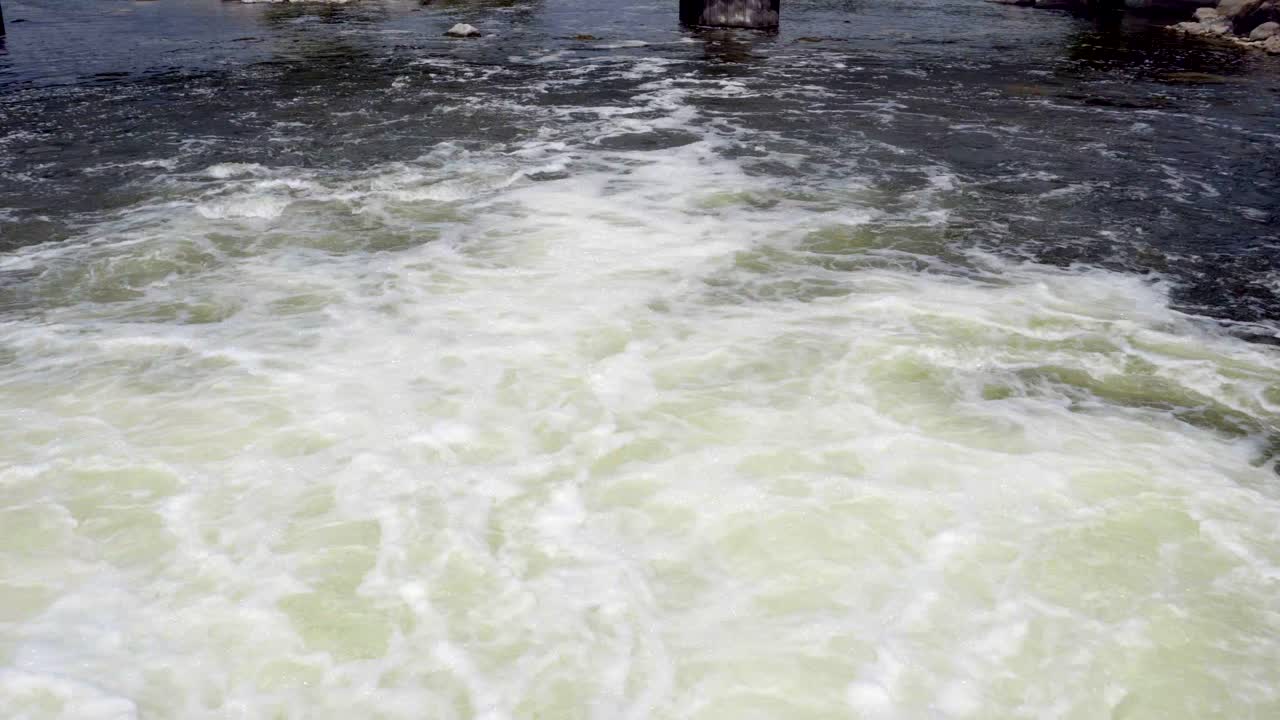 Looking down over foaming turbulent water exiting a dam in the Kawartha Buckhorn Lift locks in Ontario Canada