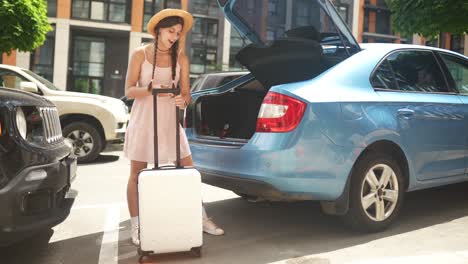 woman loading suitcase into car trunk